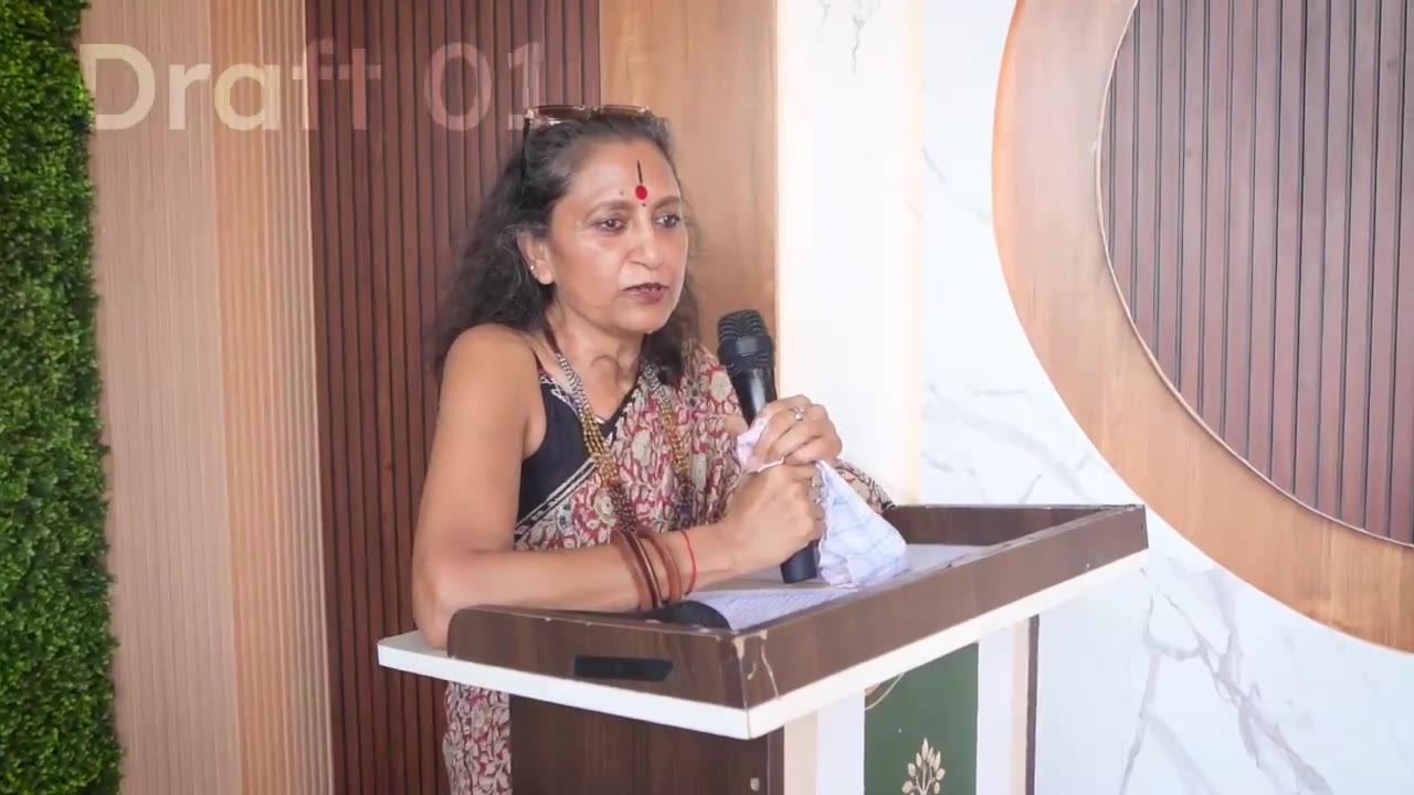 A woman in a patterned sari speaking at a lectern