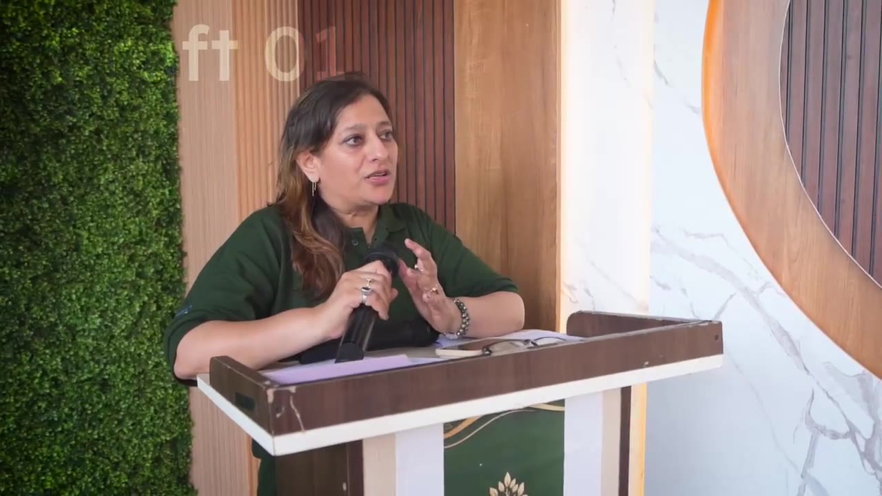 A woman in green addressing a gathering from a lectern